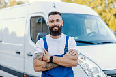istock A warehouse driver is standing with arms crossed in front of the pickup. He is driving and shipping goods to all their clients. The client can be sure that the goods will come to them on time. 1345171843
