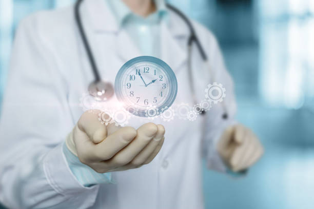Time management concept in patient care. Doctor show clock with gears on blurred background.