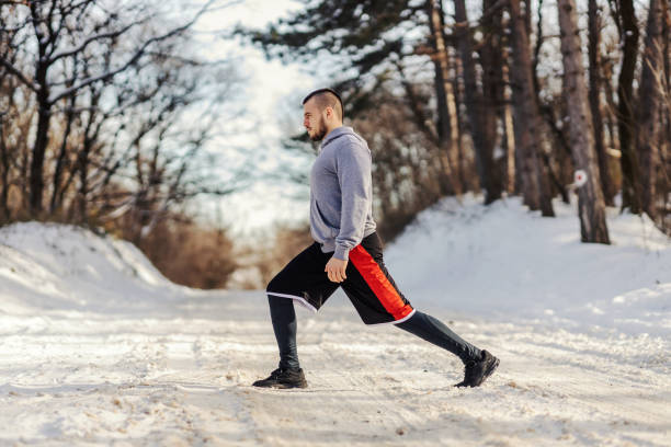 istock Fit sportsman doing stretching and warmup exercises while standing on snowy path in nature at winter. Healthy habits, winter sport, outdoor fitness 1345172505