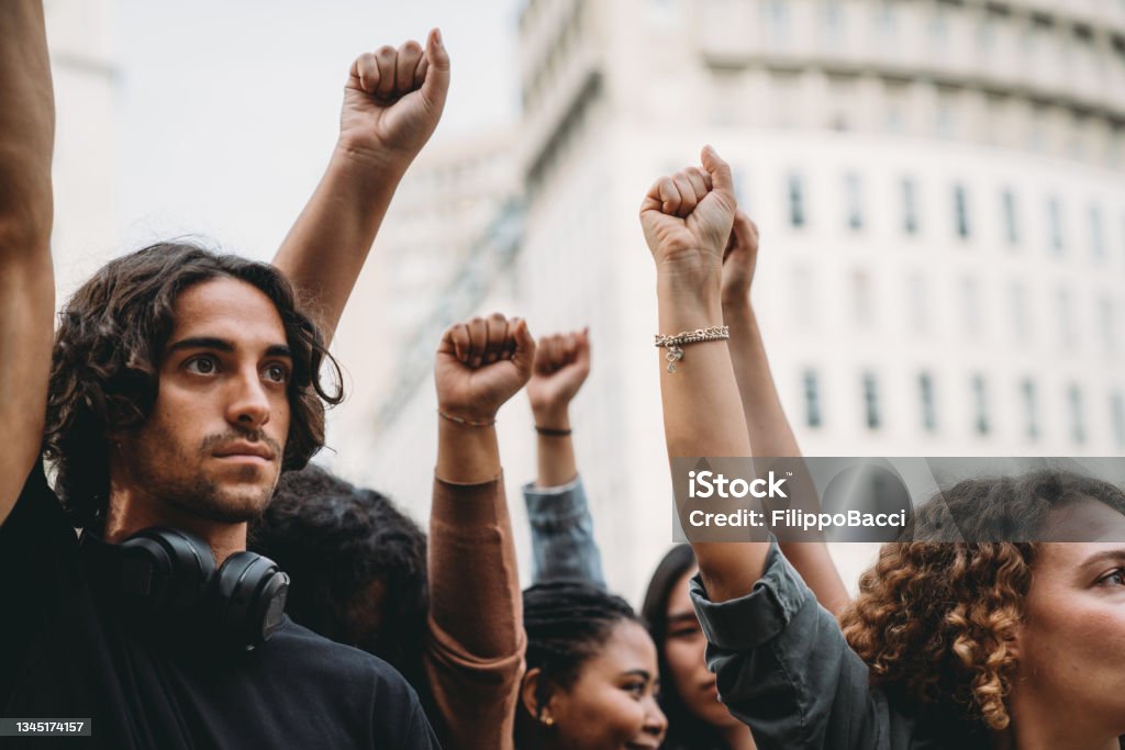 People with raised fists at a demonstration in the city People with raised fists at a demonstration in the city. Multi-ethnic group of people together on strike. Protest Stock Photo