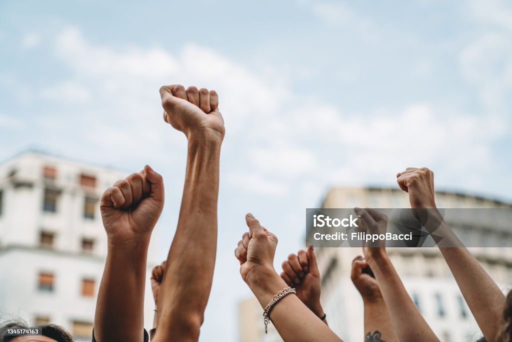 People with raised fists at a demonstration in the city People with raised fists at a demonstration in the city. Multi-ethnic group of people together on strike. Protest Stock Photo