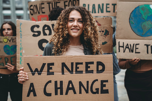 A group of young adult people are marching together on strike against climate change