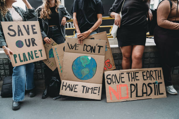 la gente sostiene pancartas mientras van a una manifestación contra el cambio climático - cambio climático fotografías e imágenes de stock