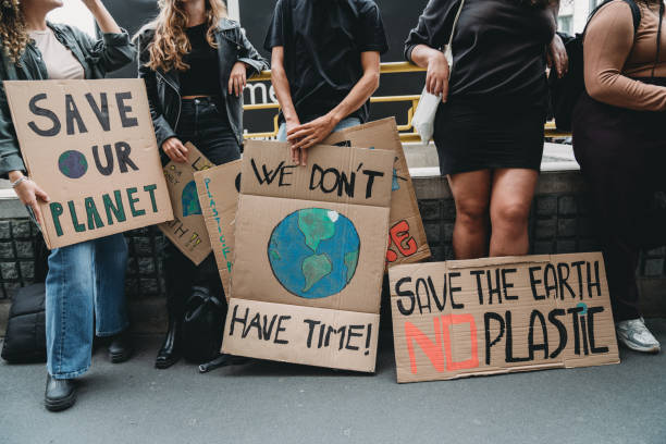 le persone tengono cartelli mentre stanno andando a una manifestazione contro il cambiamento climatico - global warming smog city pollution foto e immagini stock