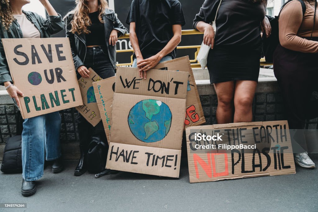 People are holding banner signs while they are going to a demonstration against climate change People are holding banner signs while they are going to a demonstration against climate change. Protest against global warming. Climate change protest concept. Climate Change Stock Photo