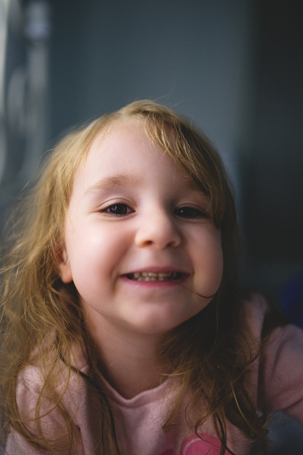 Pretty little girl with green eyes playing with a yellow wig. Girl is an oriental hispanic.