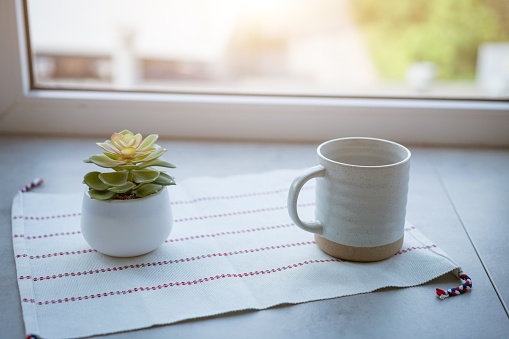 mug and flowerpot on windowsill, morning concept