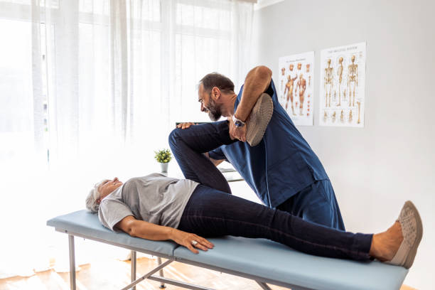 We're going to take recovery one step at a time Male doctor chiropractor or osteopath fixing womans leg with hands movements during visit in manual therapy clinic chiropractic adjustment photos stock pictures, royalty-free photos & images