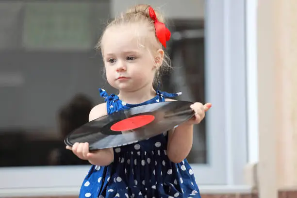 Photo of little girl sitting with records on the steps