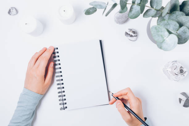istock Female hands write in blank notebook with pencil 1345186296