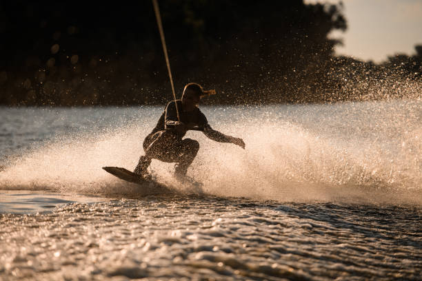 istock Energy sportive wet man riding fast on wakeboard on splashing water surface 1345186586