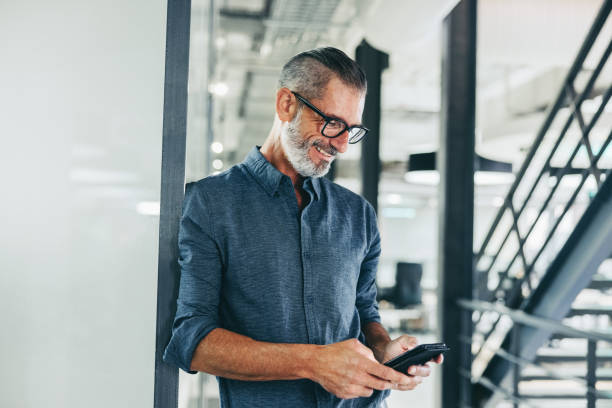 istock Cheerful businessman sending a text message in an office 1345188280