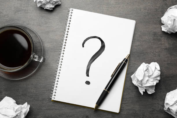 istock Flat lay composition of crumpled paper balls and notebook with question mark on grey table 1345189282