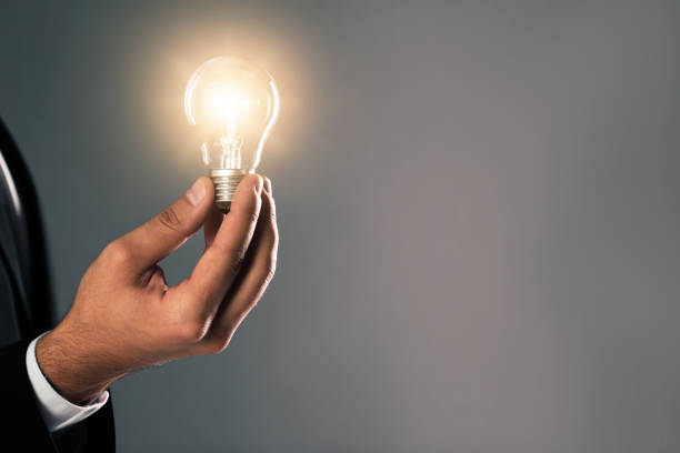 istock Idea concept. Businessman with glowing light bulb on grey background, closeup 1345189491