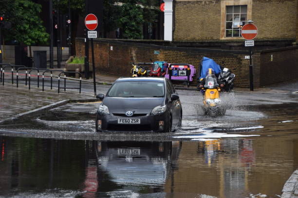 Flooded street in London, UK London, UK - August 7 2021: A car splashes through a flooded Farringdon Lane in central London after a day of heavy rain. climate crisis photos stock pictures, royalty-free photos & images