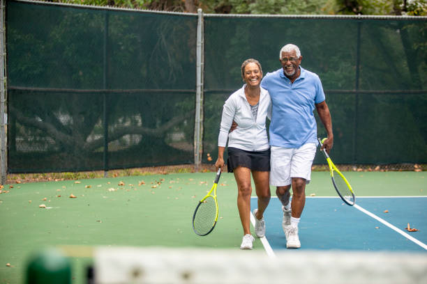 älteres schwarzes paar auf dem tennisplatz - tennis active seniors healthy lifestyle senior men stock-fotos und bilder