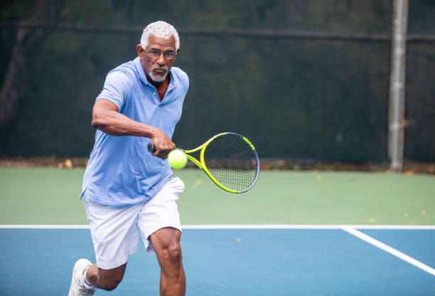 senior black man spielt tennis - tennis active seniors healthy lifestyle senior men stock-fotos und bilder