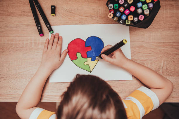 día mundial de concienciación sobre el autismo. la mano de los niños saca el corazón de los rompecabezas multicolores. concepto de atención de salud mental - autism fotografías e imágenes de stock