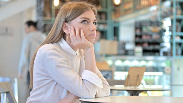 istock Pensive Young Woman Thinking in Cafe 1345198383
