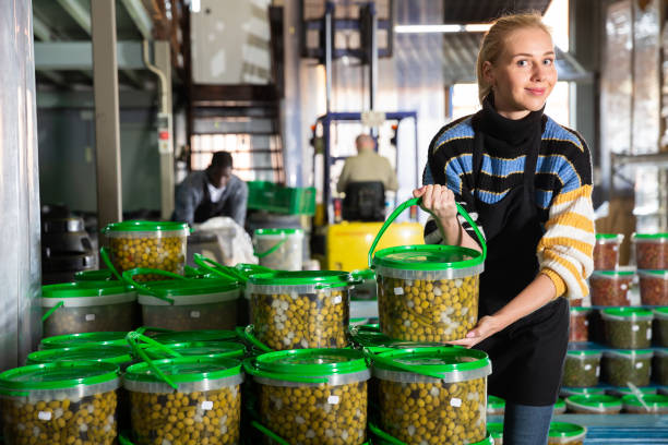 istock Girl arranging plastic buckets with pickled olives 1345198777