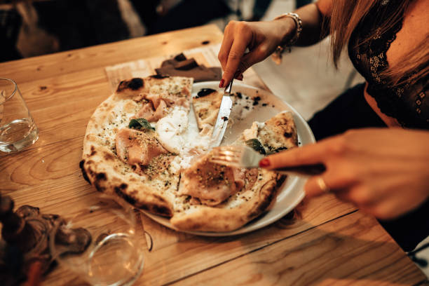 istock woman eating a pizza at the restaurant 1345200268