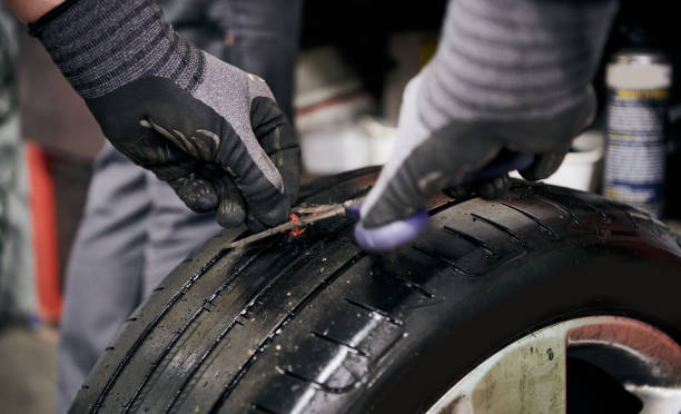 istock Vulcanizer Fixing a Punctured Hole by Inserting an Injection Mould before Injecting Natural Crude Rubber into a Used Punctured Tire in a Car Repair Shop Indoors 1345200560