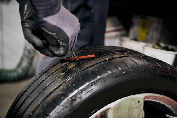 istock Vulcanizer Fixing a Hole by Inserting a Mould before Injecting Natural Crude Rubber into a Hole in a Used Punctured Tire in a Car Repair Shop Indoors 1345200569