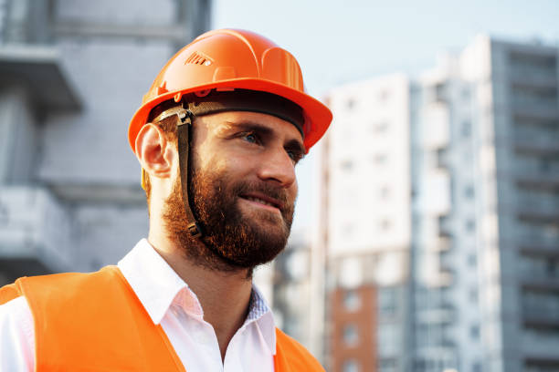 istock Builder wearing hardhat and safety vest standing on a commercial construction site 1345202052