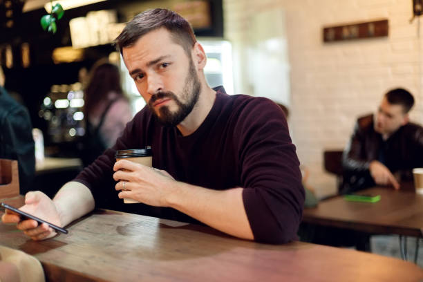 istock Young hipster guy texting with his mobile phone at the bar 1345202996