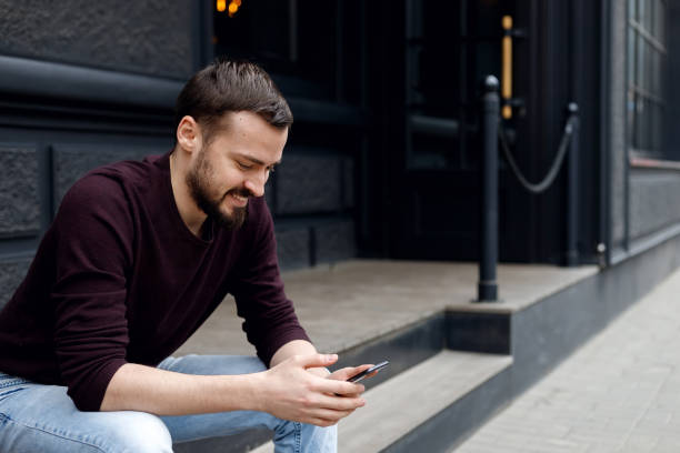 istock Happy young guy with beard relaxing with modern device outdoors 1345203000