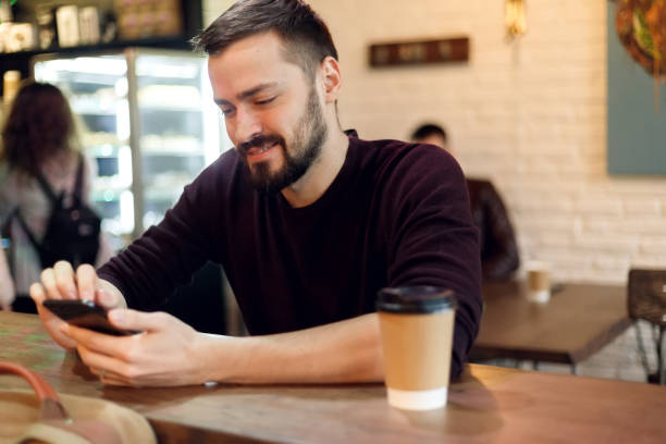 istock Young hipster guy texting with his mobile phone at the bar 1345203002