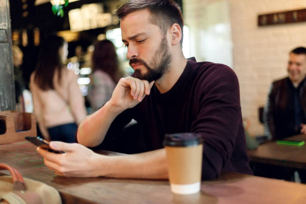 istock Young hipster guy texting with his mobile phone at the bar 1345203058