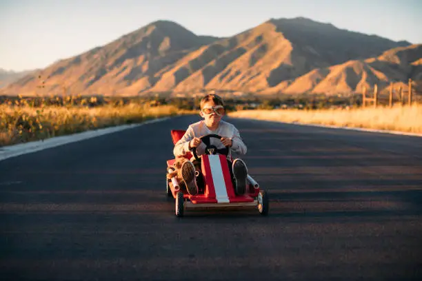 A young boy is racing in his homemade soap box race car. Image taken in Utah, USA.