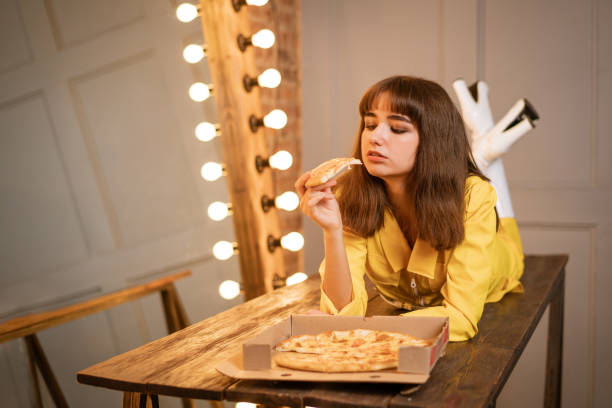 istock Young woman sitting eating pizza 1345207634