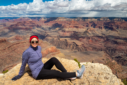 Mature woman sitting on the edge of the south rim of the Grand Canyon.