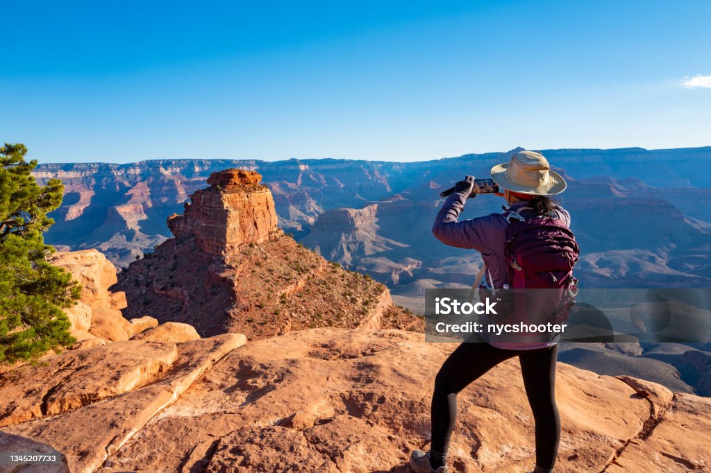 scenic view of the South Rim of the Grand Canyon Scenic view of the South Rim of the Grand Canyon. Mature woman on the edge of Canyon  taking a photo with smartphone. Grand Canyon National Park Stock Photo