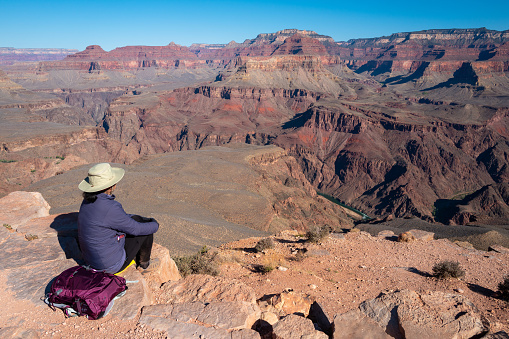 female hiker enjoying scenic view of the South Rim of the Grand Canyon on the Kaibab trail