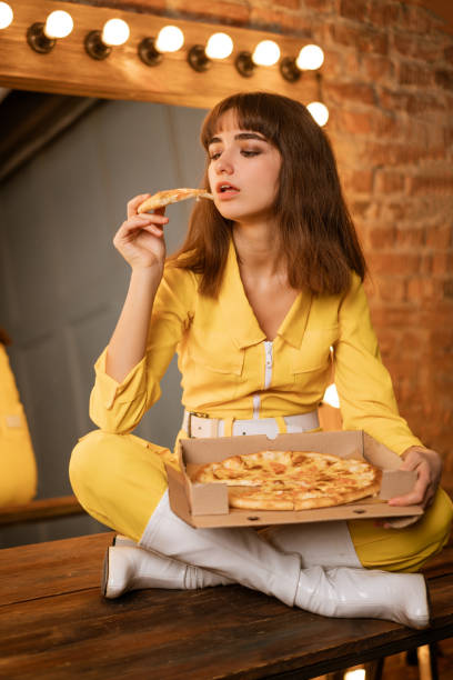 istock Young woman sitting eating pizza 1345208418