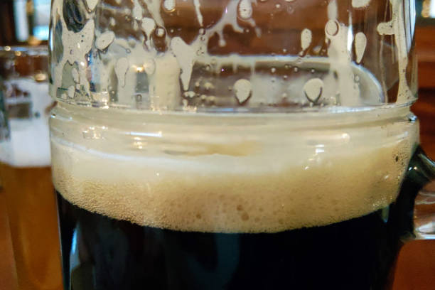 istock Mug of dark beer with foam on the table, selective focus. 1345208643