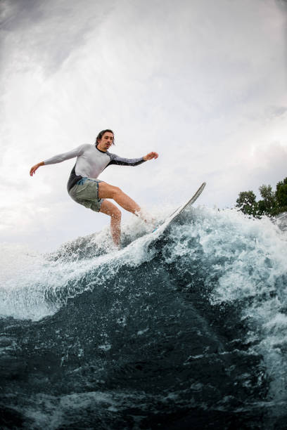istock Active sportsman skilfully riding up on wave on wakesurf board. 1345208979