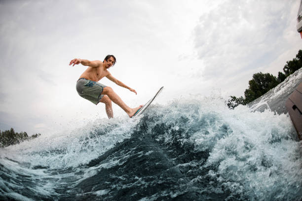 istock energy sportive man balancing on wakesurf board on splashing wave 1345209728