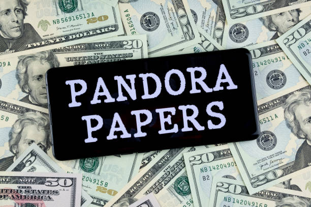 PANDORA PAPERS words seen on smartphone placed on dollar bills. stock photo