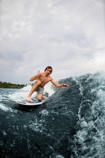 istock Active man show hand gesture riding the wave on surf style wakeboard 1345210149