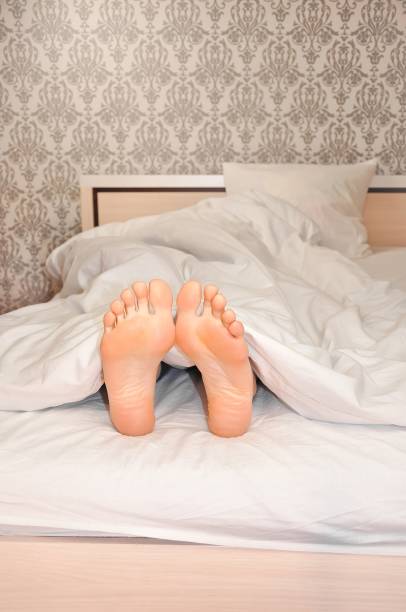 istock Woman's feet under the blanket in the morning 1345210699