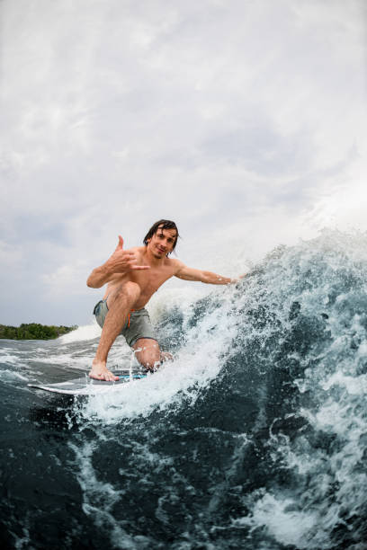 istock Active man rides the wave on surf style wakeboard and touches the wave with one hand 1345213801