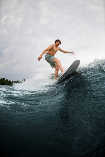 istock handsome man on wakesurf board and riding river wave on summer day 1345213844