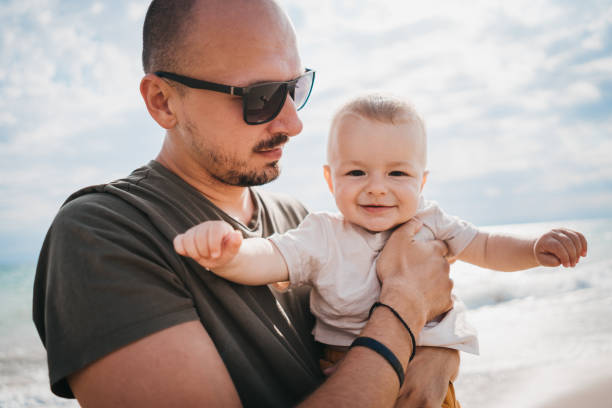 istock Father carries his son to the beach 1345213927