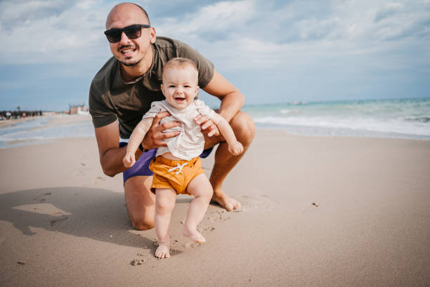 The father teaches the son the first steps on the beach