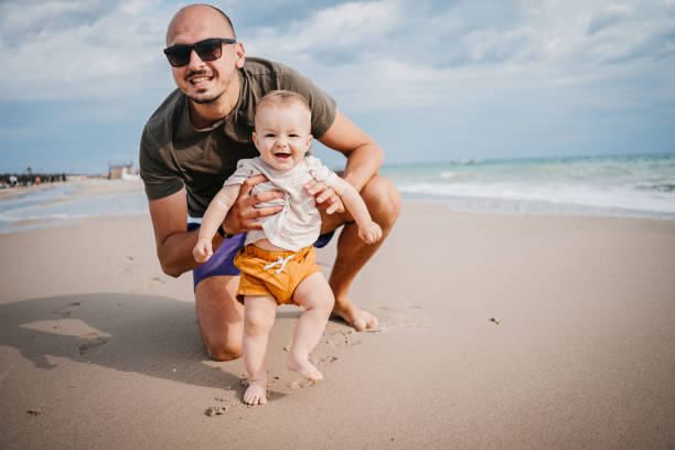 The father teaches the son the first steps on the beach stock photo