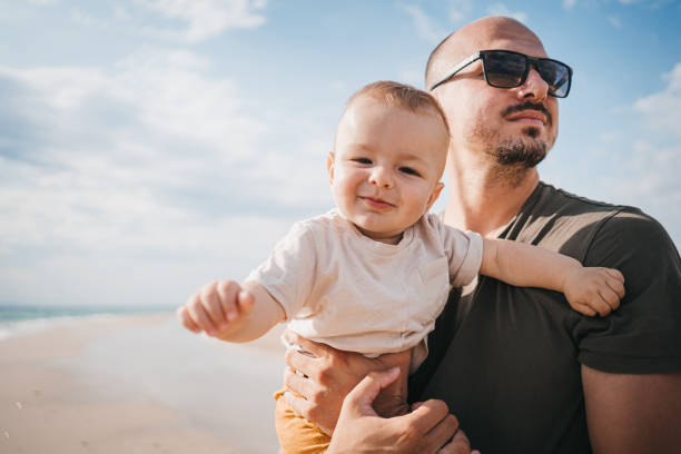 Father carries his son to the beach stock photo